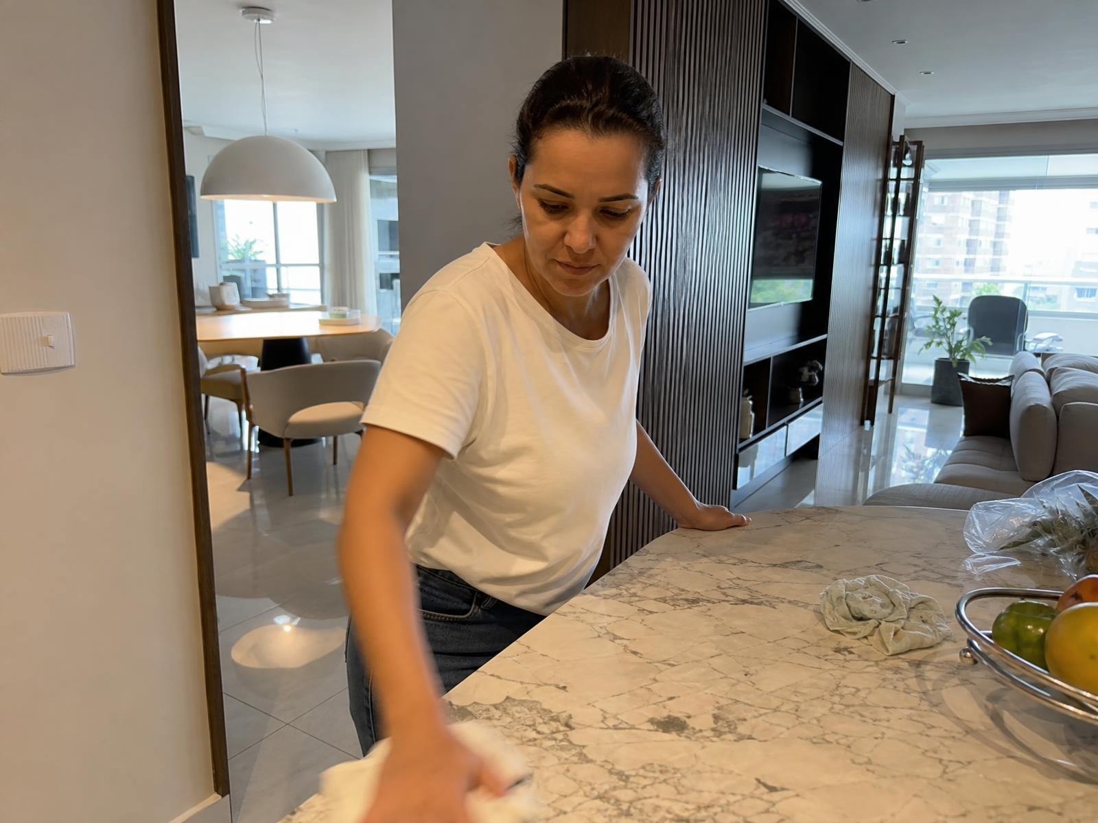 Diarista limpando a mesa da sala de um apartamento em Brasília